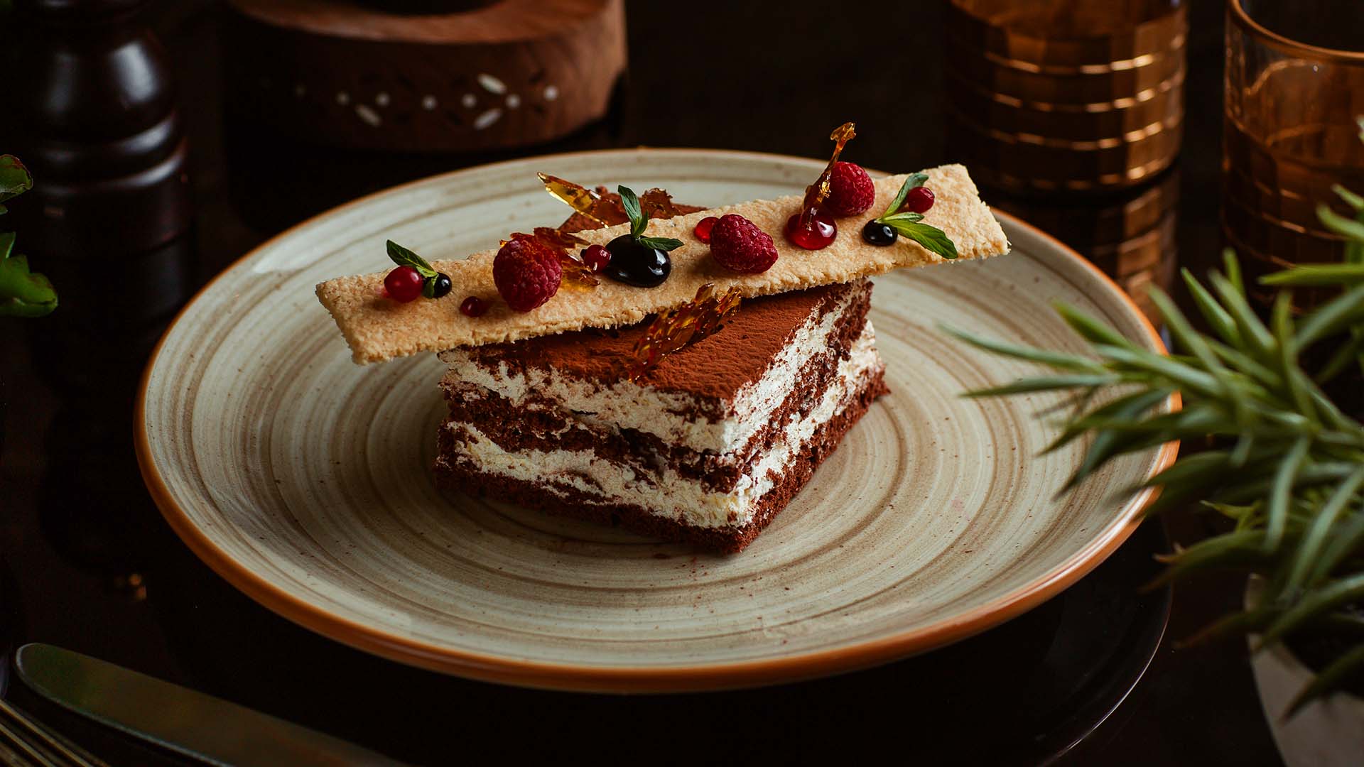 Schokoladen-Tiramisu mit Beeren und einer knusprigen Dekoration auf einem Teller serviert.
